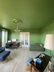 Grønt stueinteriør med skrivebord og sofa