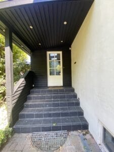 Modern house entrance with black tiled stairs