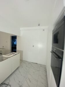 Moderne køkken med marmorfliser og indbyggede apparater.