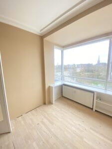 Bright empty room with large windows and wooden floor